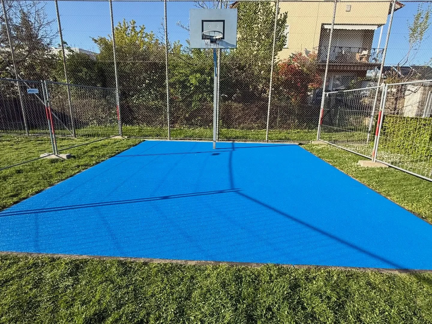 Himmelblaues Spielfeld mit Ballfangzaun auf einer Sportanlage