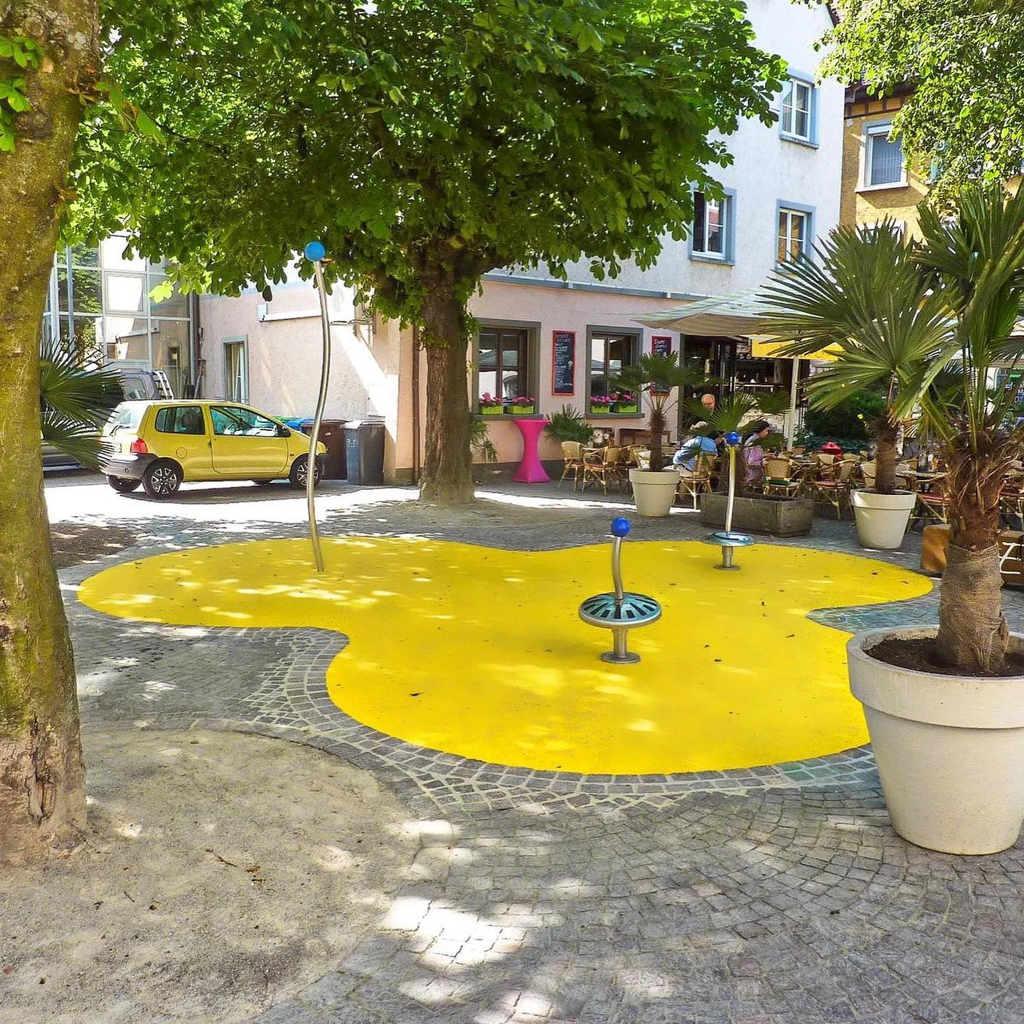 Zitronengelbe Freiform mit Wasserspiel auf einem Platz