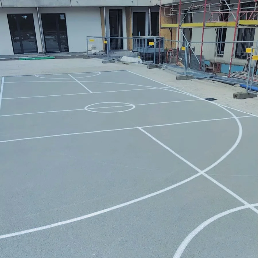Basketballfeld mit lichtgrauem Sportbelag und weißer Linierung