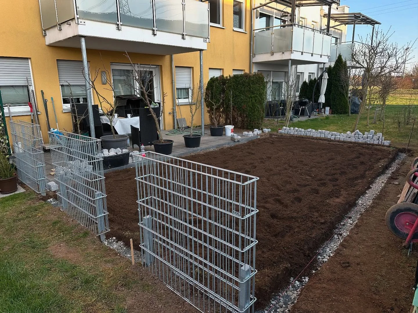 Gabionen und vorbereitetes Pflanzbeet vor einem Wohnhaus