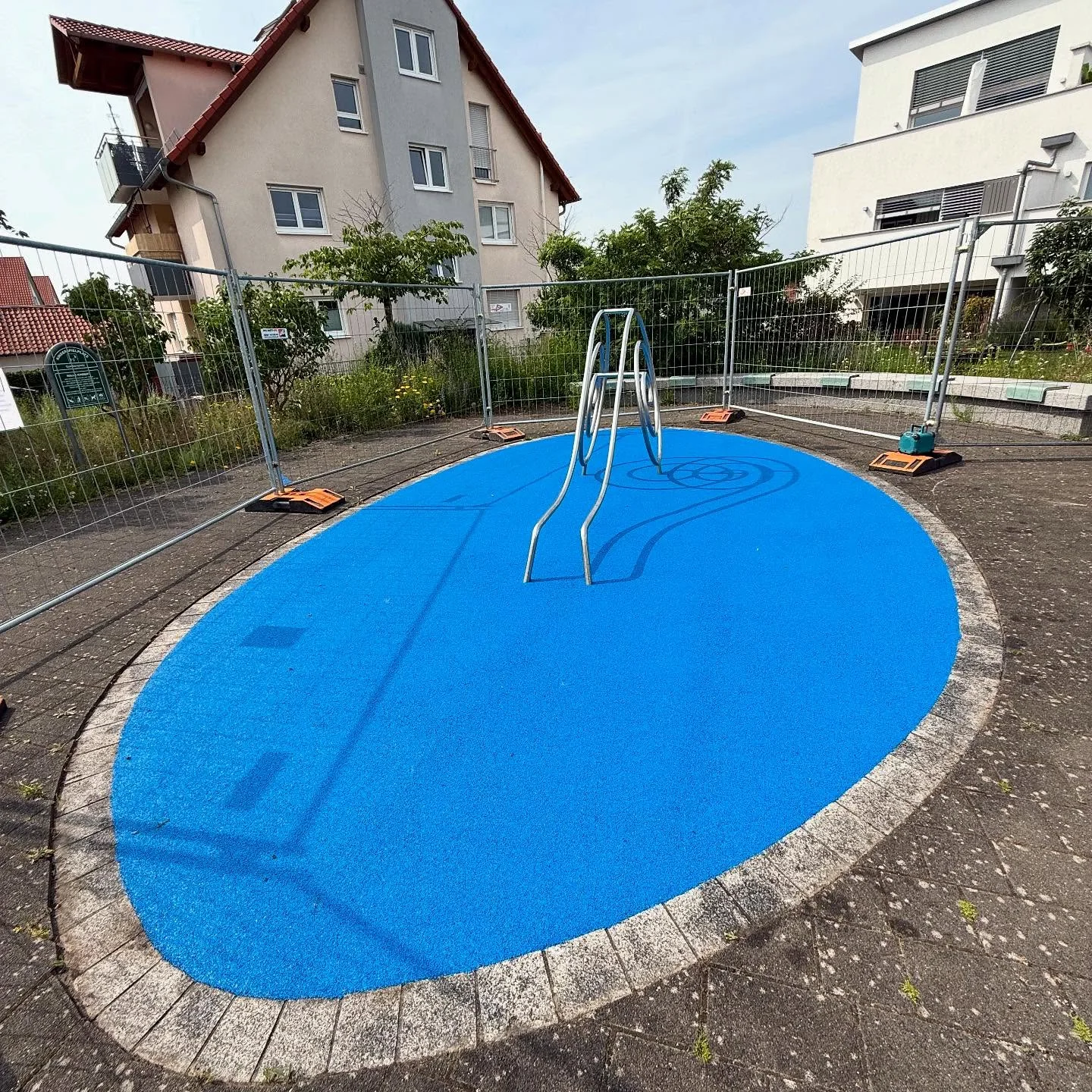 Ovale himmelblaue Fallschutzfläche mit Kletterbogen, frisch eingebaut
