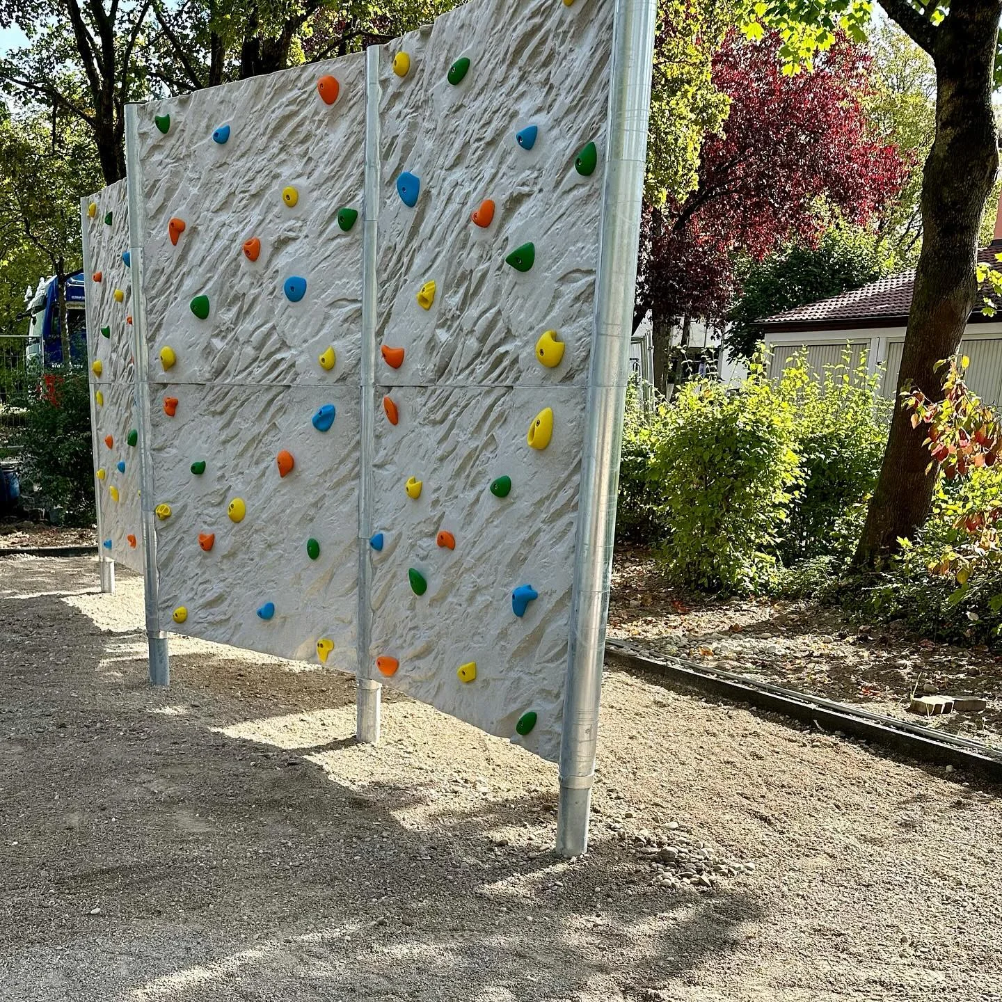 Freistehende Kletterwand mit farbigen Griffen auf einem Schulhof